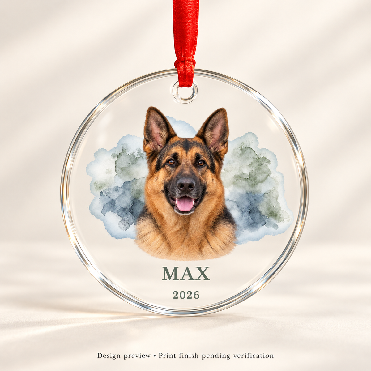 Design preview of Max German Shepherd keepsake glass ornament with watercolor portrait, name, 2026 and red ribbon in a studio setting. Print finish pending verification.