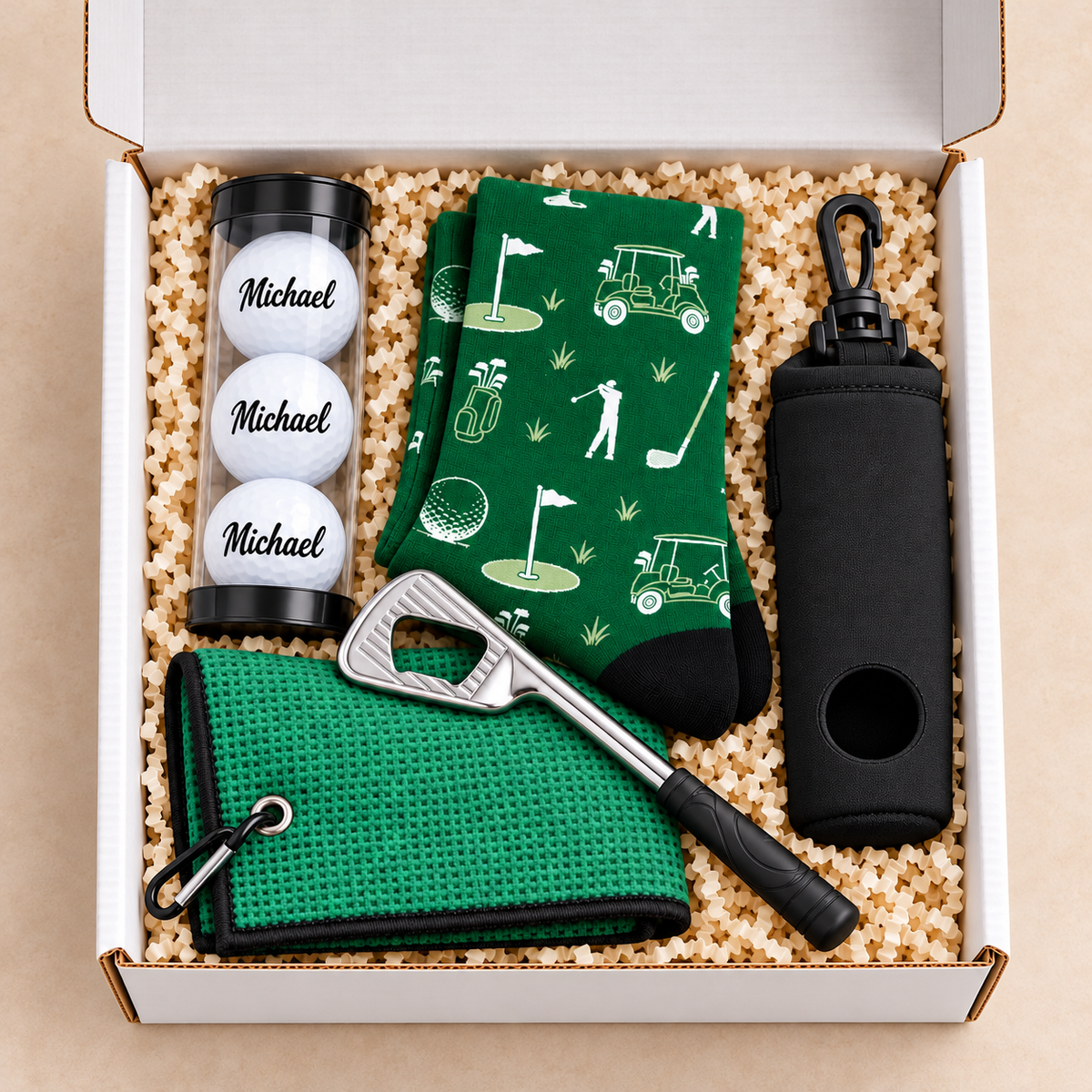 Overhead view of an open white golfer gift box with personalized golf balls and neatly arranged green golf accessories
