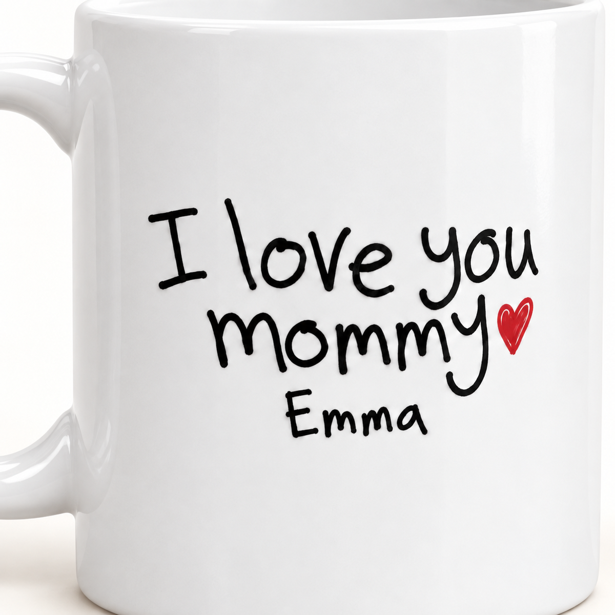 Close-up of the sample child handwriting “I love you mommy,” Emma’s name, and a red heart printed on a white ceramic mug.